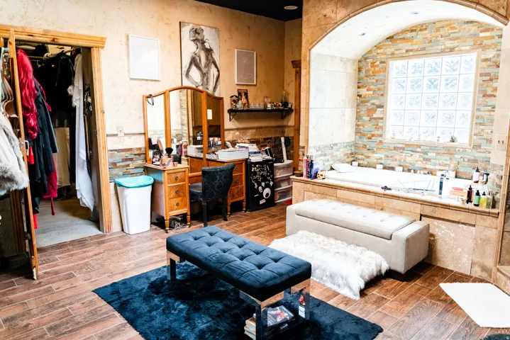 Arched alcove with a built-in tub, glass block window, and stacked stone accent wall
