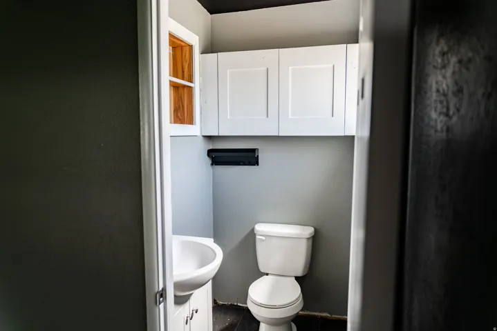 Compact powder room featuring a white porcelain toilet with a dual-flush mechanism, pedestal sink, and gray-painted walls