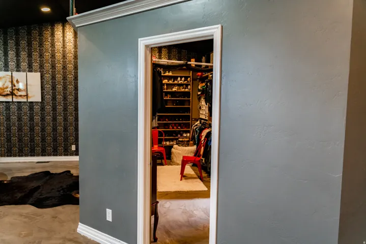Built-in closet shelving and storage, crown molding, patterned accent wall, recessed lighting, and light-colored flooring