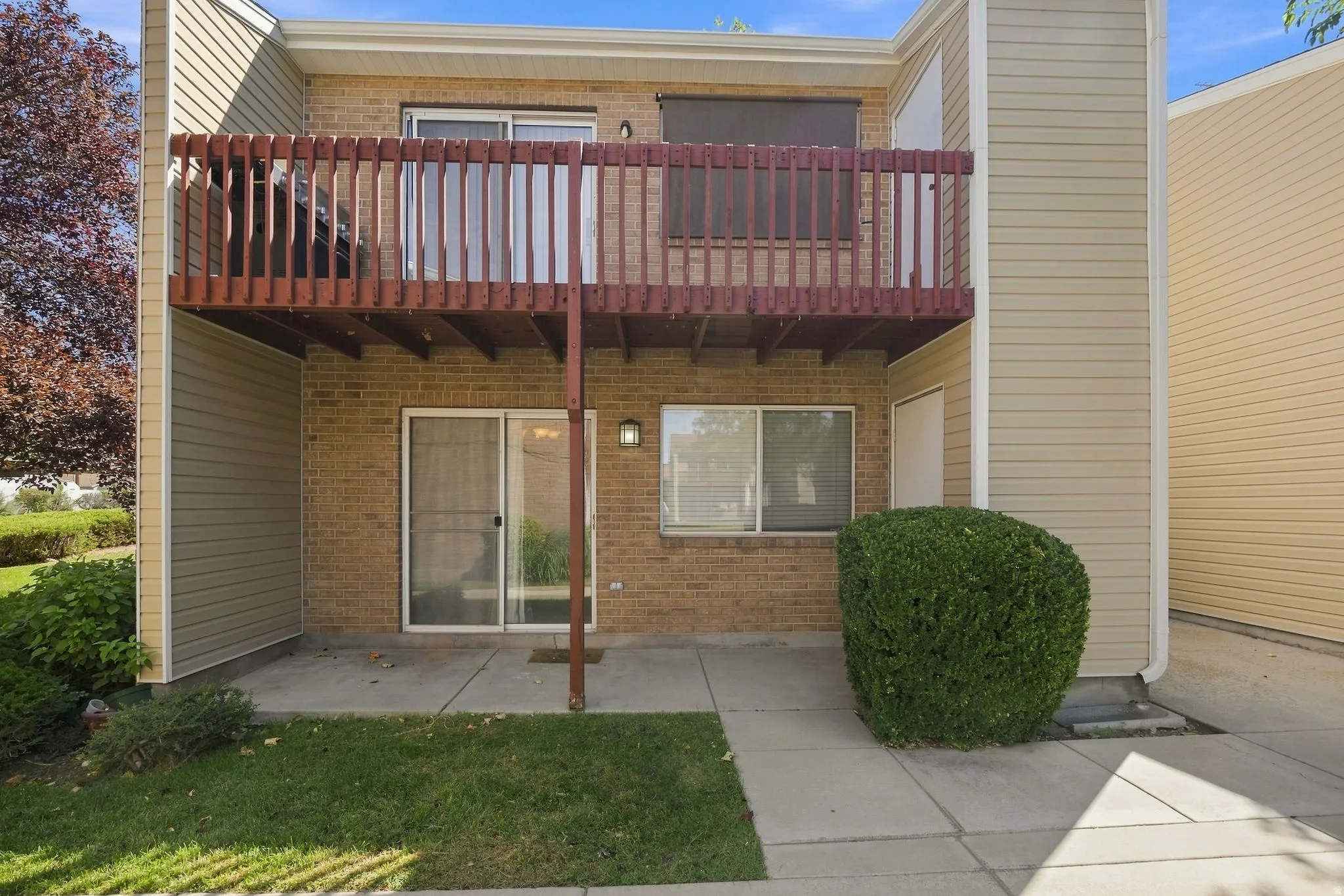 Brick exterior with a wooden balcony, sliding glass door, and an exterior light fixture