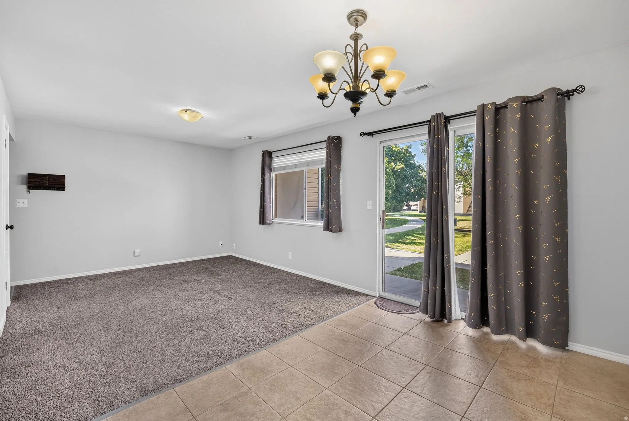 Tile flooring, carpeted area, sliding glass door, overhead light fixture, window