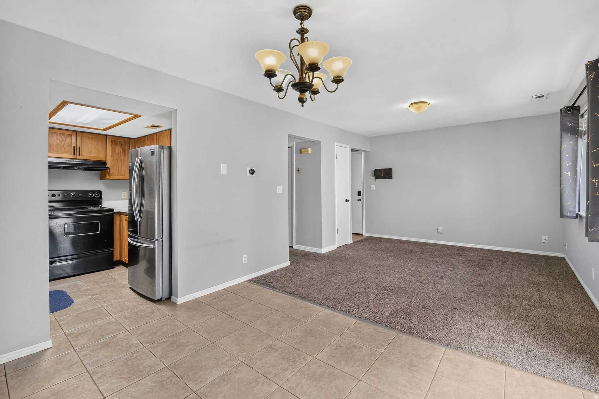 Integrated kitchen featuring stainless steel refrigerator and black range