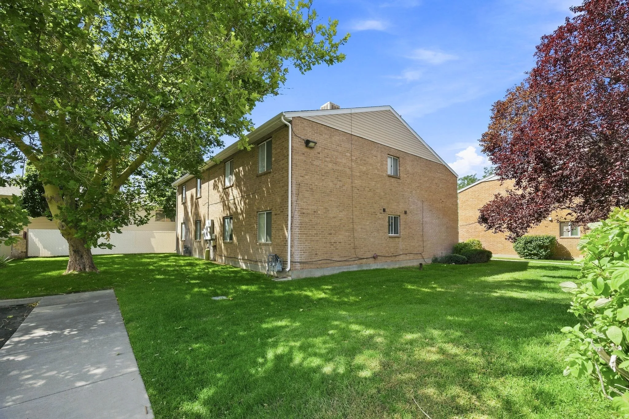 Two-story brick exterior with horizontal siding accents, multiple windows, and a concrete pathway