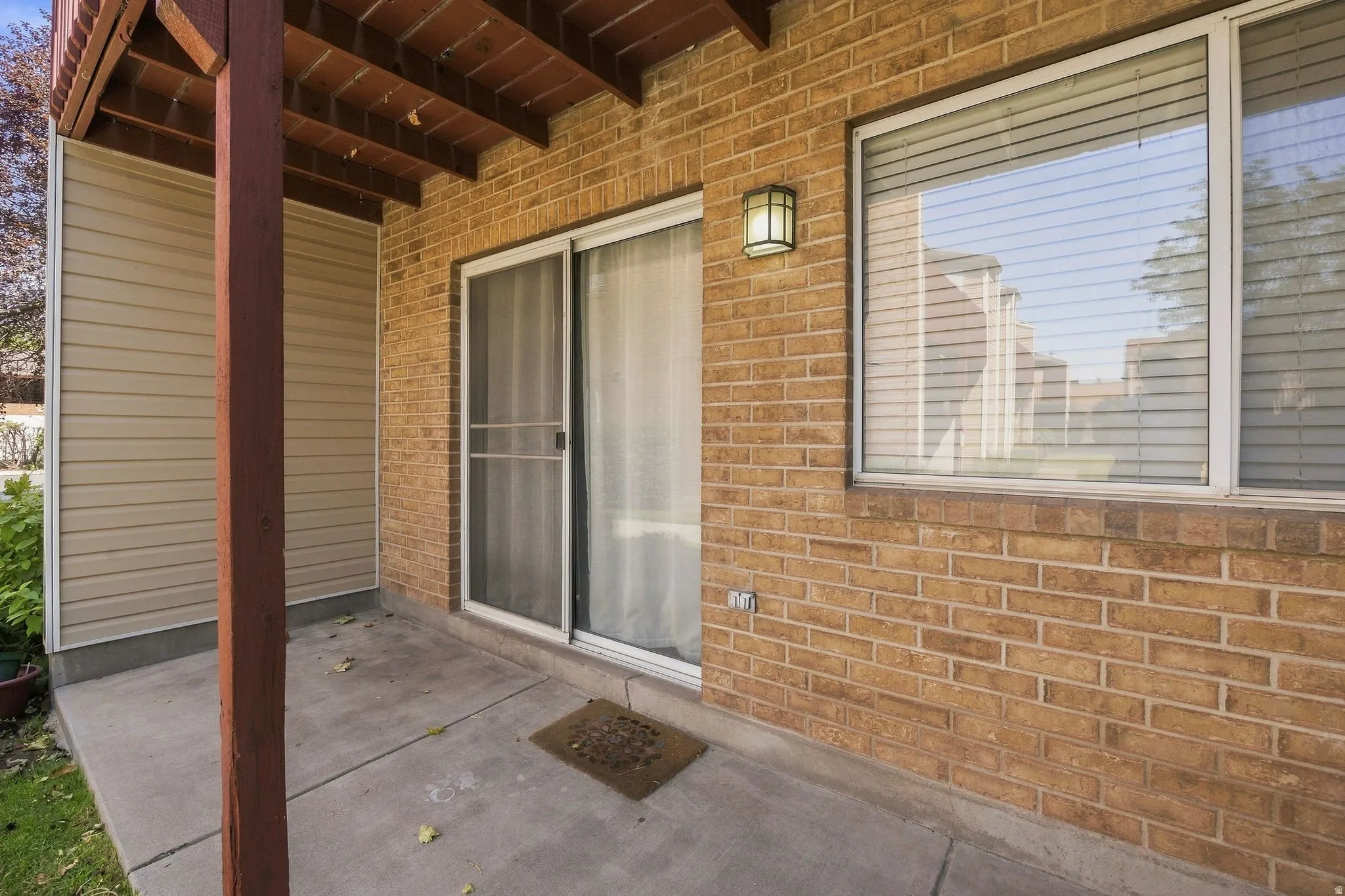 Covered patio space featuring a concrete slab, brick exterior, and vinyl siding