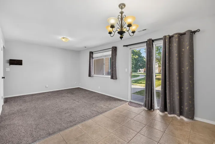 Tile flooring, carpeted area, sliding glass door, overhead light fixture, window