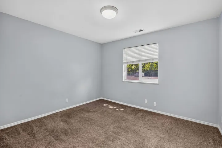 Neutral wall color, wall-to-wall carpeting, single window with blinds, ceiling-mounted light fixture, white trim