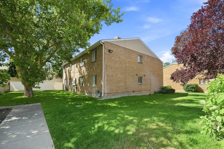 Two-story brick exterior with horizontal siding accents, multiple windows, and a concrete pathway