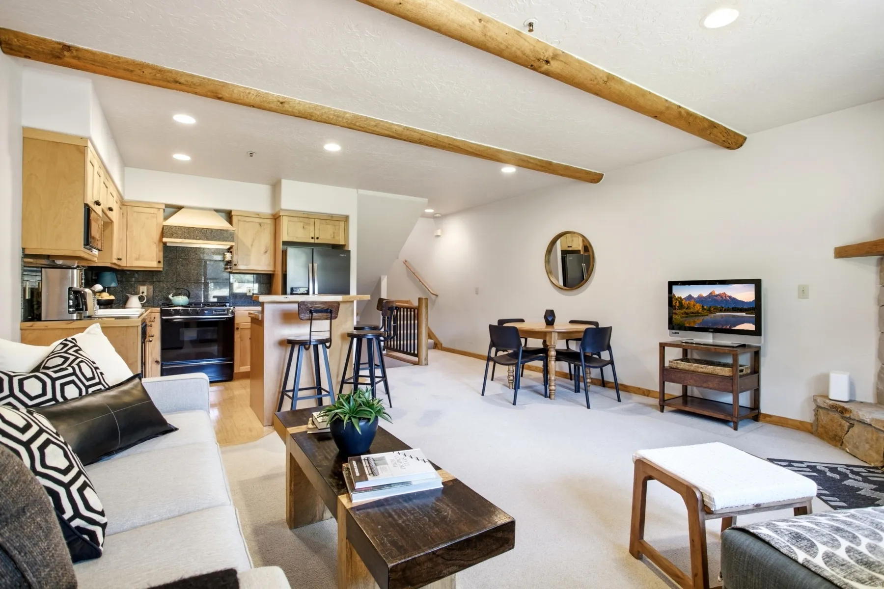 Open-concept living area with exposed wood beams and recessed lighting