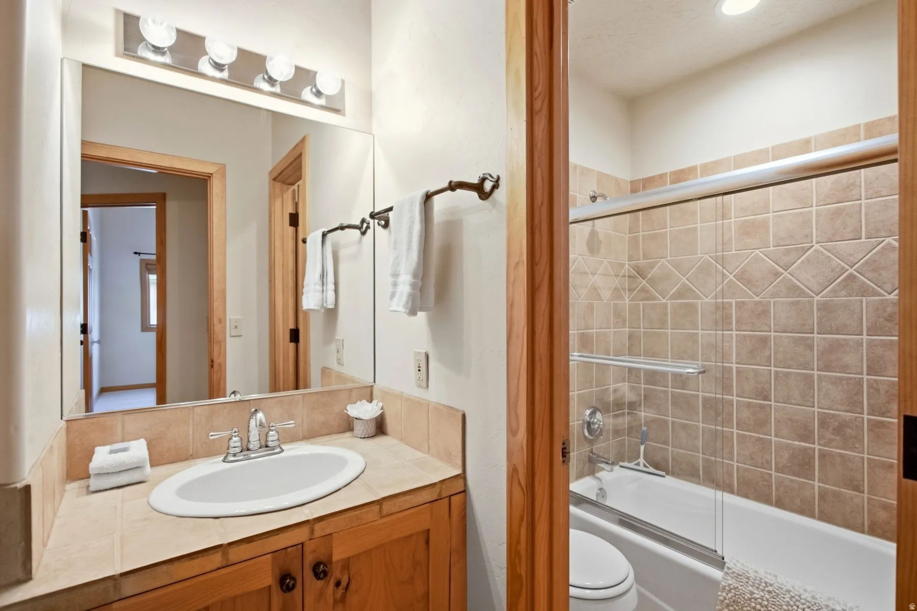 Wood-finish vanity with an integrated oval sink, chrome faucet, and tile countertop