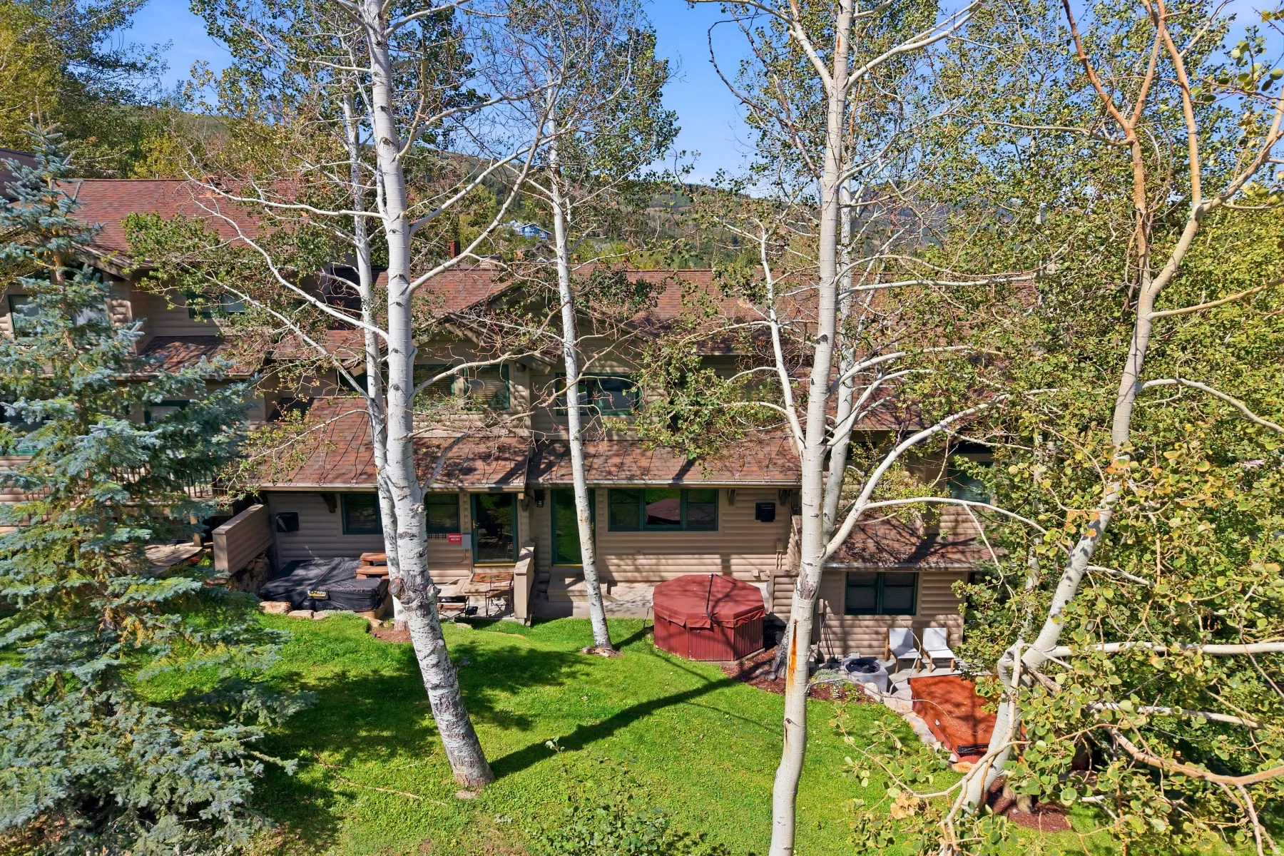 Rear exterior with multiple decks, a ground-level patio, and a hot tub