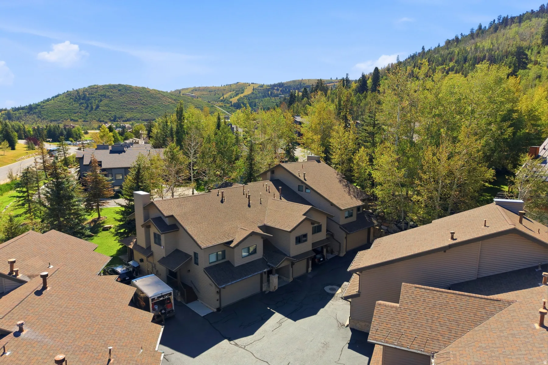Multi-story buildings with asphalt shingle roofs, surrounded by mature trees