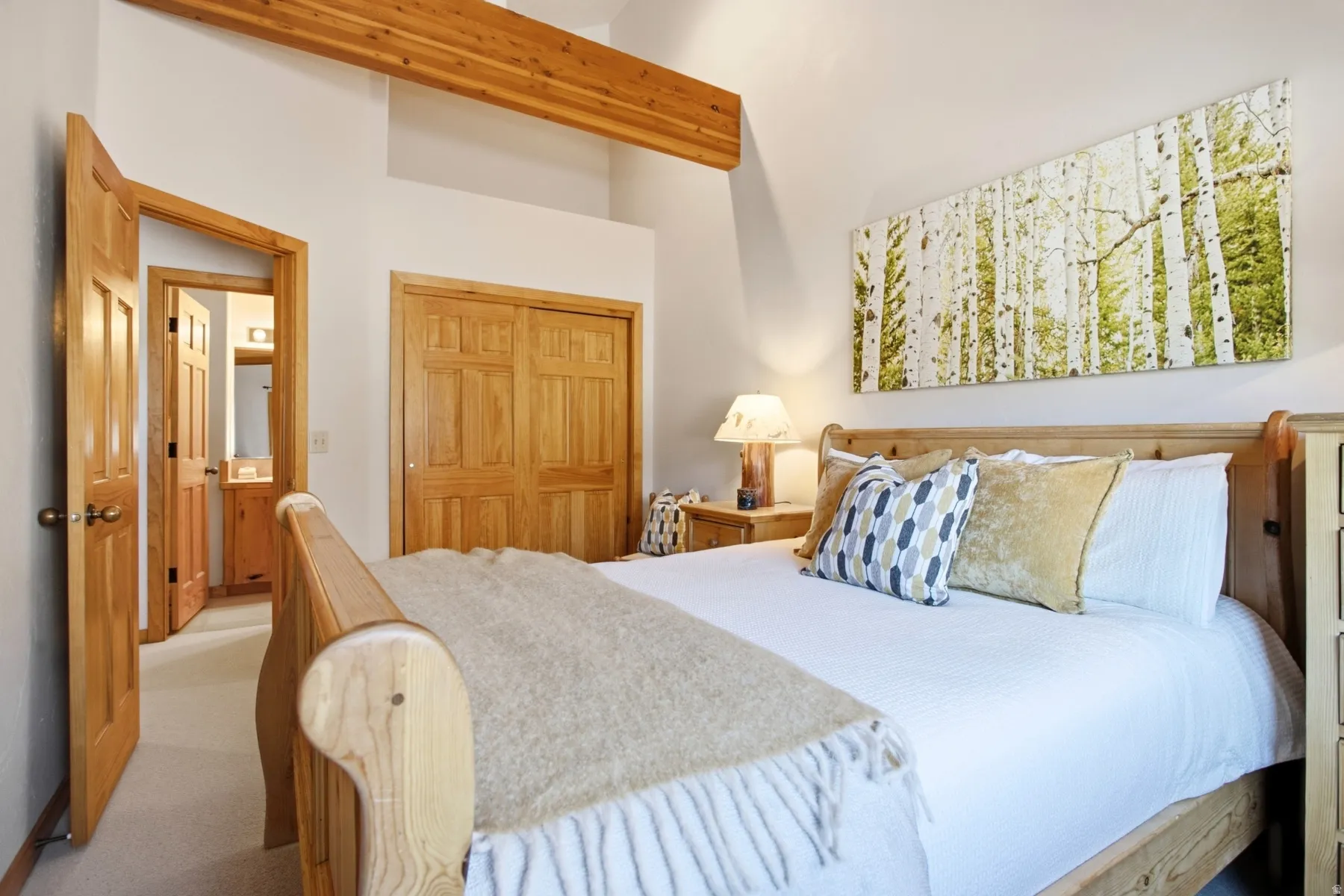 Vaulted ceiling with exposed wood beam, natural wood doors, and wood-finish sliding closet doors