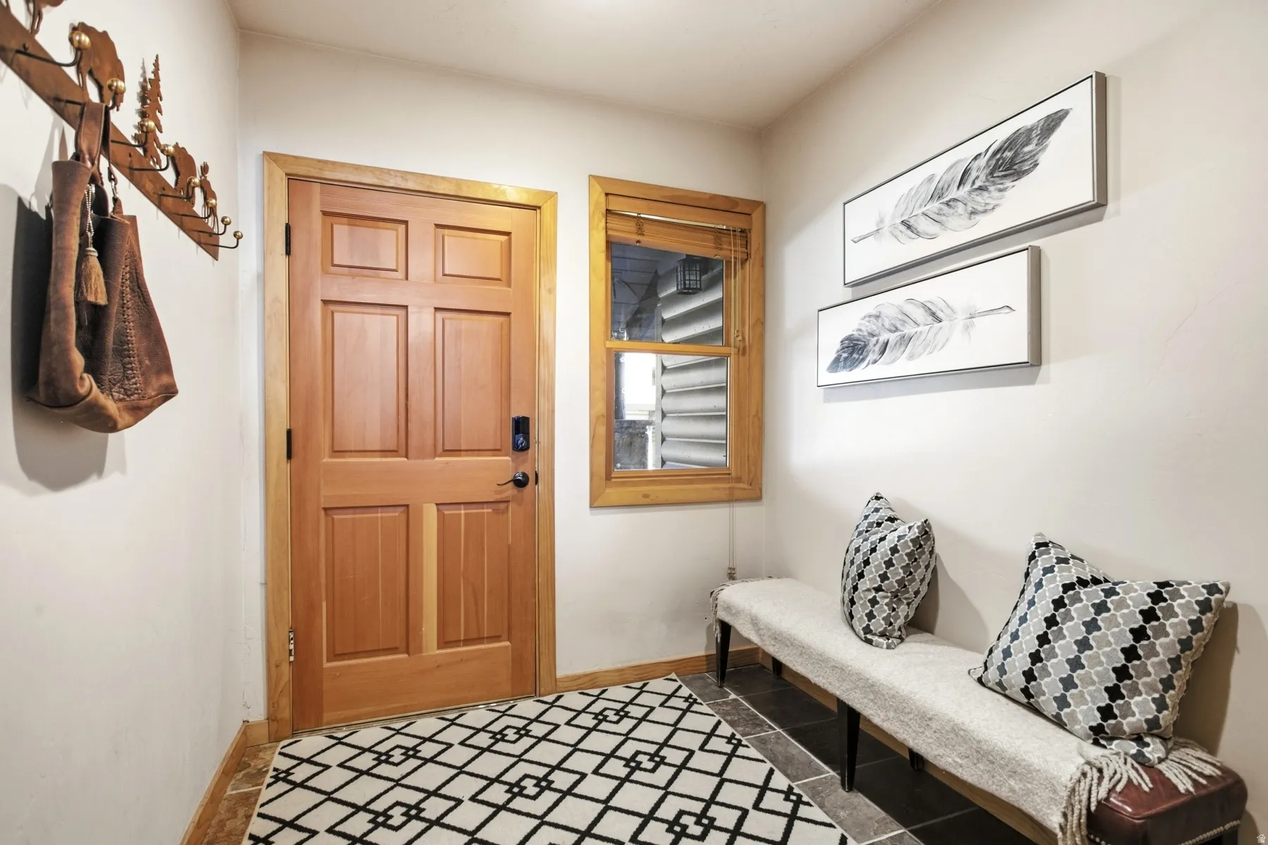 Six-panel solid wood door with dark hardware, natural wood trim, and an adjacent window with wood blinds