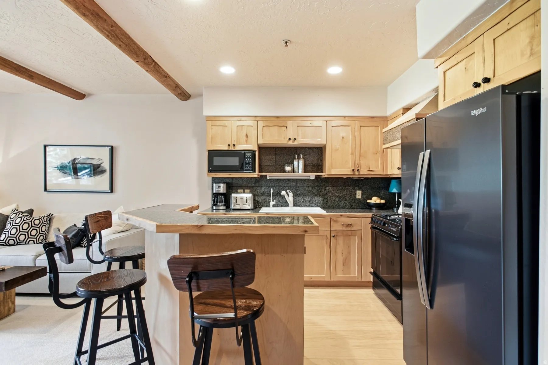 Kitchen featuring wood cabinetry, dark countertops, built-in microwave, and a black refrigerator