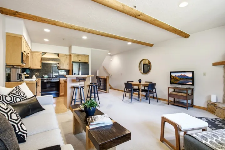 Open-concept living area with exposed wood beams and recessed lighting