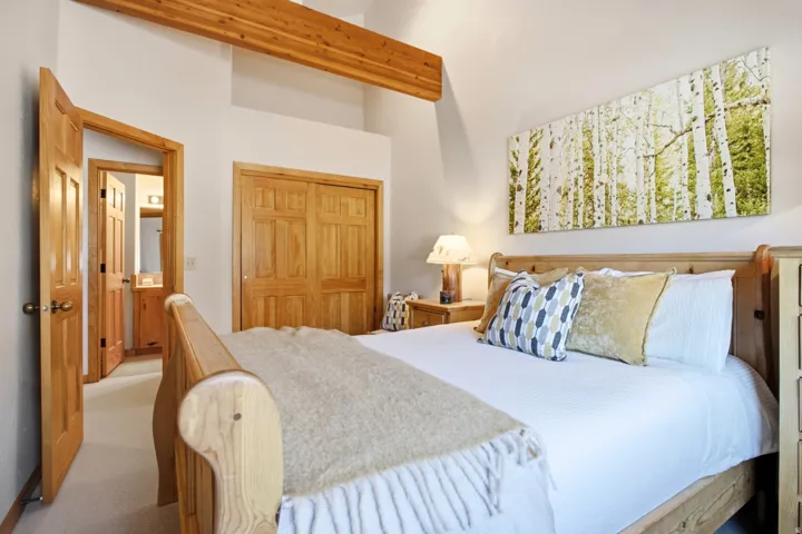 Vaulted ceiling with exposed wood beam, natural wood doors, and wood-finish sliding closet doors