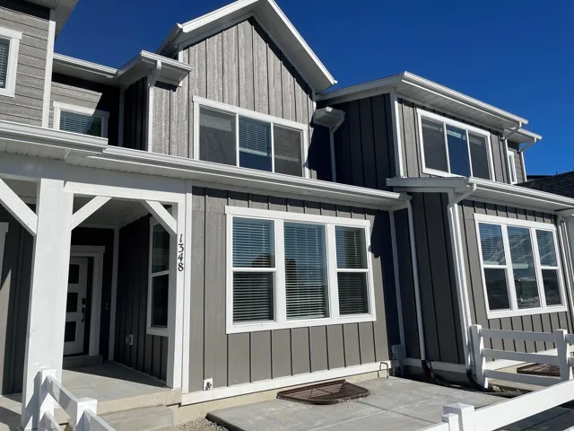Gray vertical siding, white trim, white window frames, covered entry, and white porch railing
