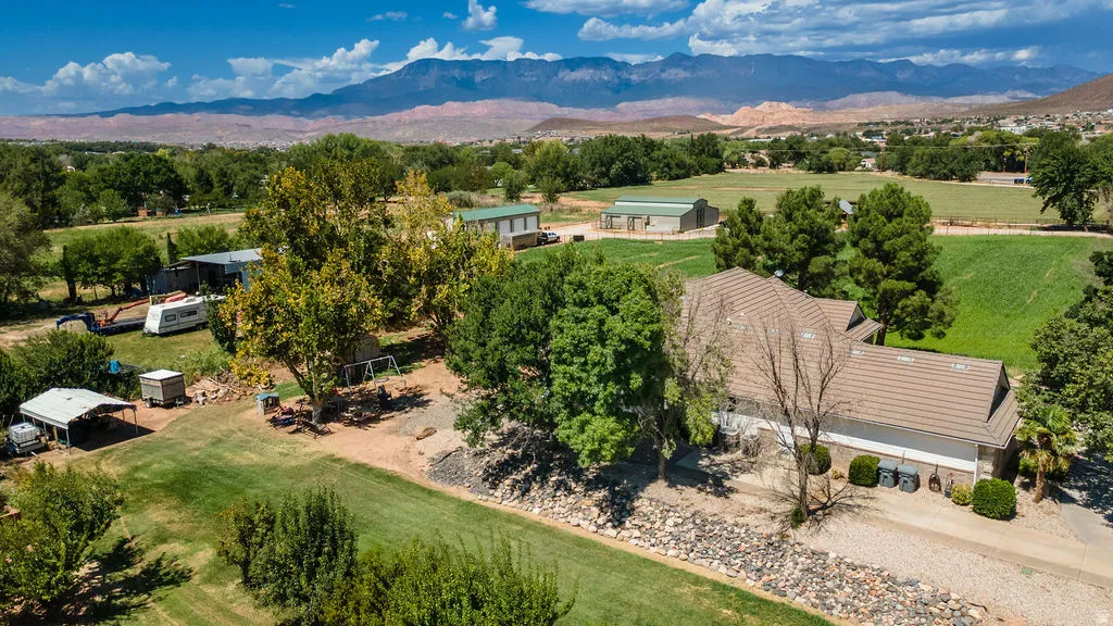 Expansive property featuring a tiled roof residence, detached structures, and extensive green landscaping with mature trees