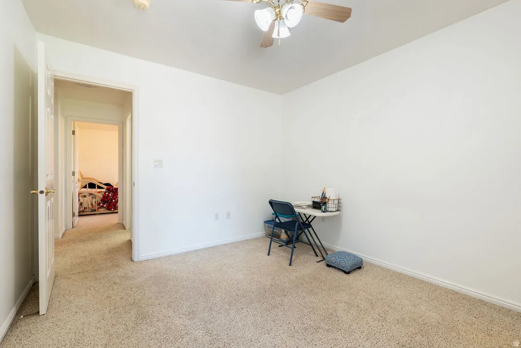 Textured carpet flooring, white walls, white trim, and a ceiling fan with integrated lighting