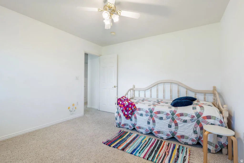 Carpeted flooring, white painted walls, and a ceiling fan with integrated lighting