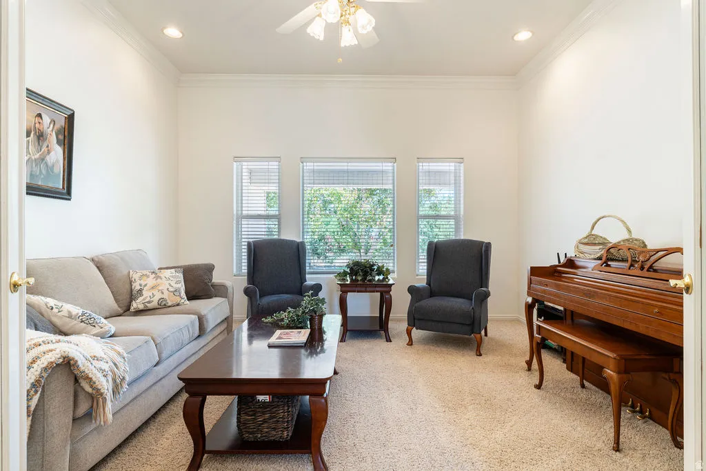 Recessed lighting, ceiling fan, crown molding, multiple windows, and light-colored carpeting