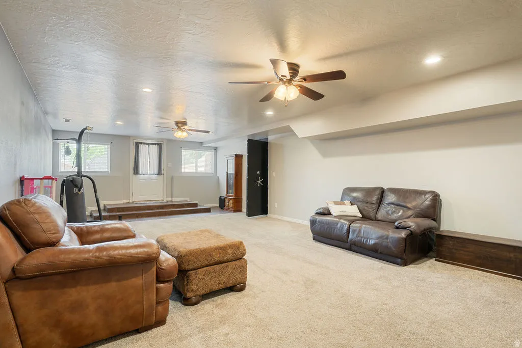 Recessed lighting, ceiling fans, and neutral carpet flooring
