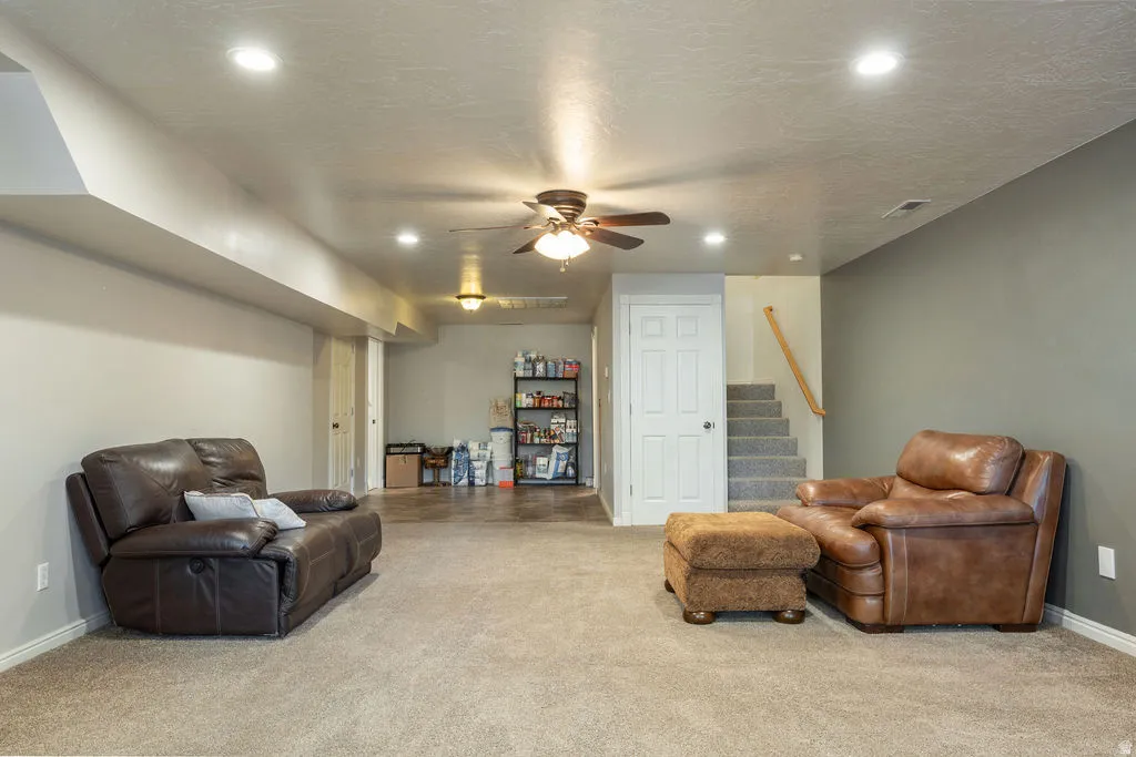 Recessed ceiling lighting, ceiling fan, carpeted flooring, and a stairway with a wood handrail
