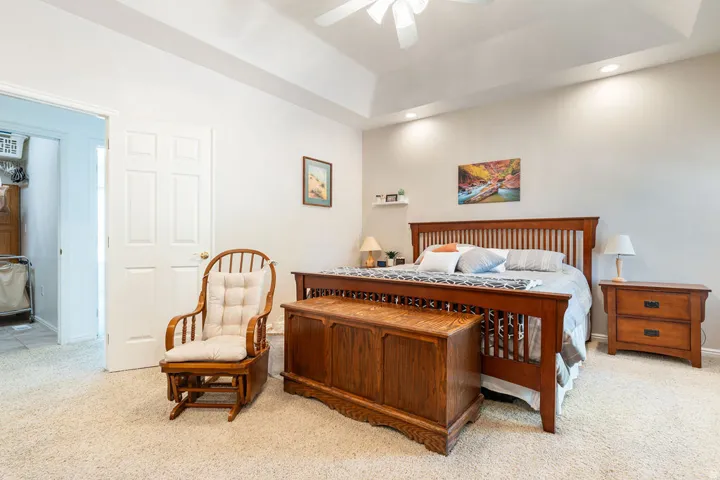 Tray ceiling with recessed lighting, ceiling fan, and light-toned carpeting