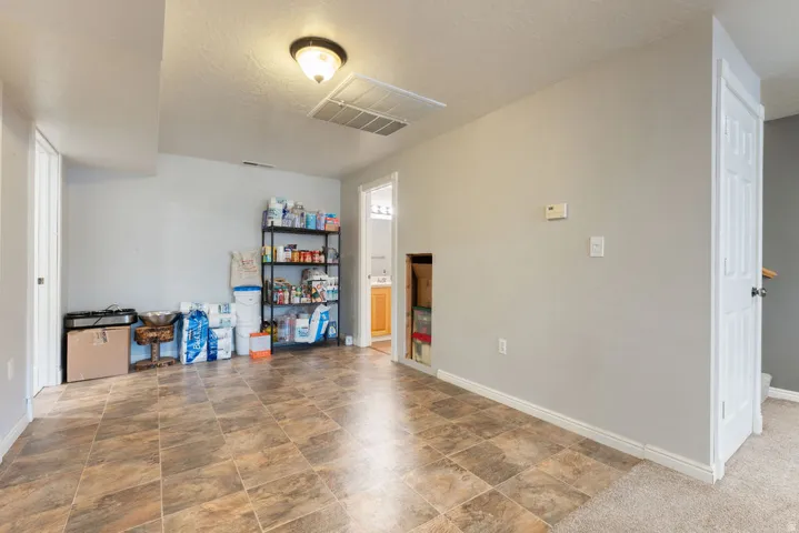 Spacious room featuring tile-finish flooring, light gray wall paint, white trim, and a ceiling-mounted light fixture