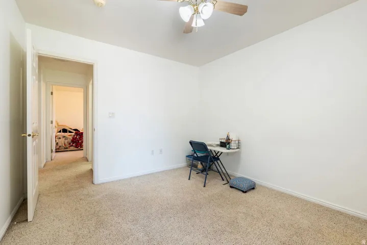 Textured carpet flooring, white walls, white trim, and a ceiling fan with integrated lighting