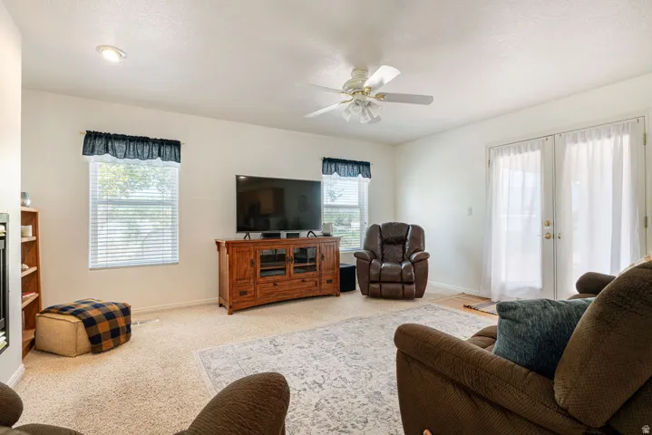 Recessed ceiling lighting, ceiling fan, white paneled French doors, and neutral carpet flooring