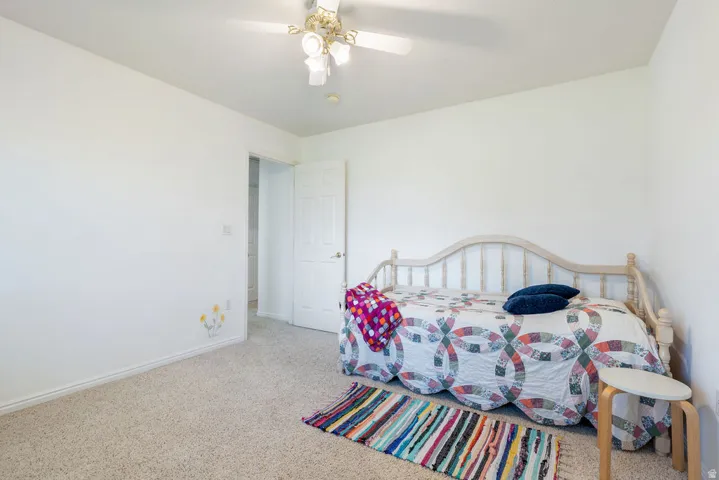 Carpeted flooring, white painted walls, and a ceiling fan with integrated lighting