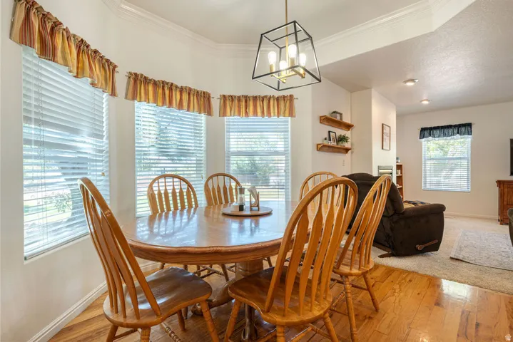 Bay window with blinds, wood-finish flooring, recessed lighting, and a geometric light fixture