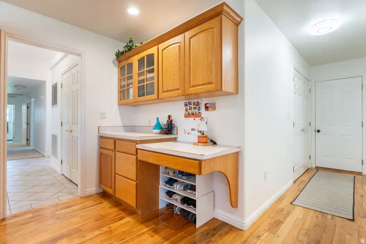 Built-in desk area with wood cabinetry, glass-front upper cabinets, and a laminate countertop