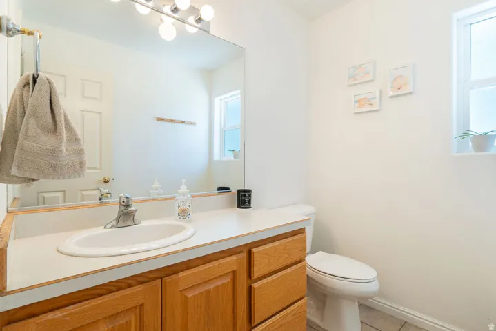 White oval sink with a chrome faucet, set into a light-toned countertop, above wood-finish cabinetry