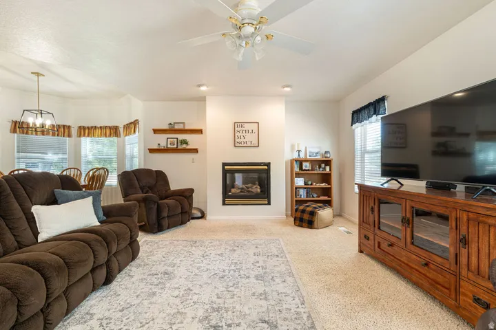 Carpeted living area with a built-in fireplace, recessed lighting, and a ceiling fan