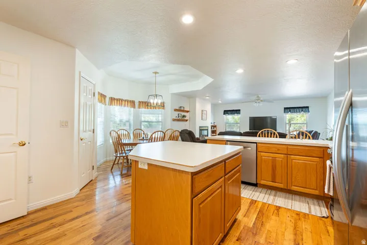 Kitchen featuring wood-finish flooring, recessed lighting, wood cabinetry, stainless steel dishwasher, and an island with counter space