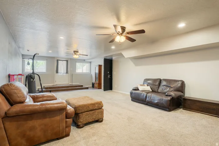 Recessed lighting, ceiling fans, and neutral carpet flooring