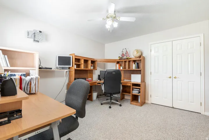 Built-in cabinetry, recessed shelving, textured carpeting, ceiling fan, and double-door closet