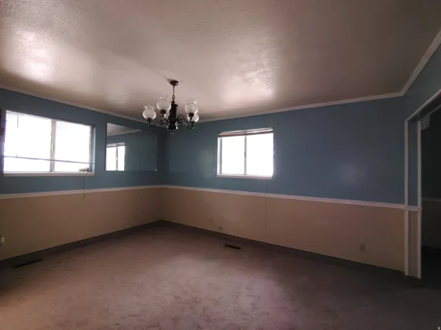 Carpeted room featuring two windows, a chandelier, and a two-tone wall treatment with chair rail molding