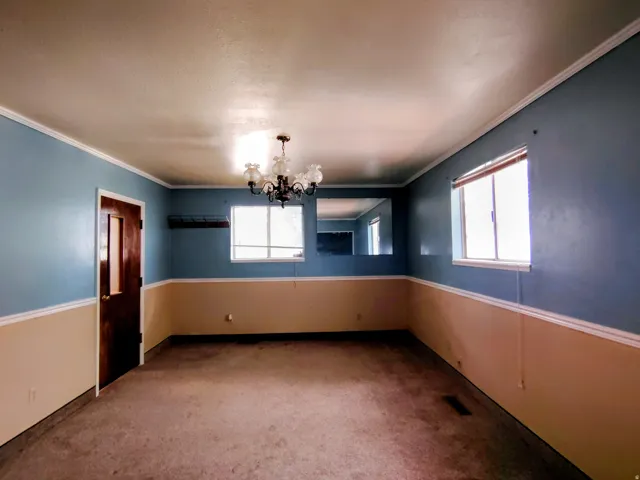 Expansive room featuring two-tone wall paint, crown molding, and carpet flooring
