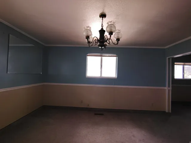 Room featuring a multi-bulb chandelier, a window, and a wall mirror