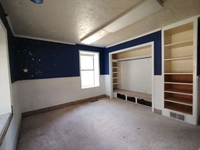 Carpeted room featuring a built-in closet with shelving, an integrated bench with storage, and an additional built-in bookshelf