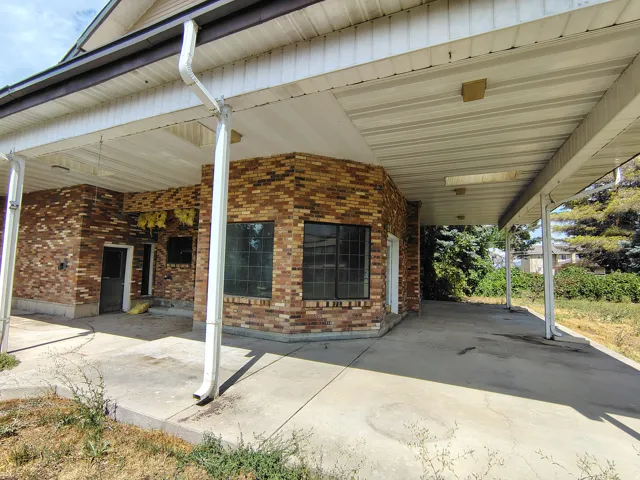 Brick exterior with multiple windows and a covered concrete walkway