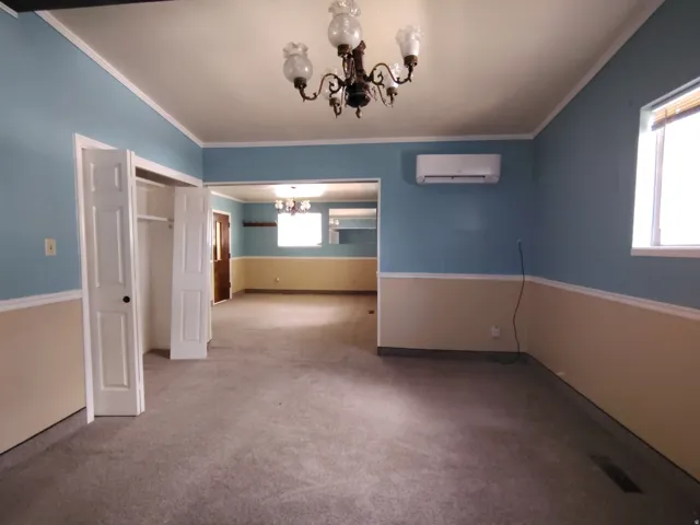 Carpeted room with a chandelier, two-tone painted walls, and a wall-mounted air conditioning unit