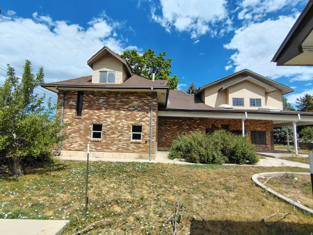 Brick exterior with a multi-level roofline, featuring an attached carport and mature landscaping
