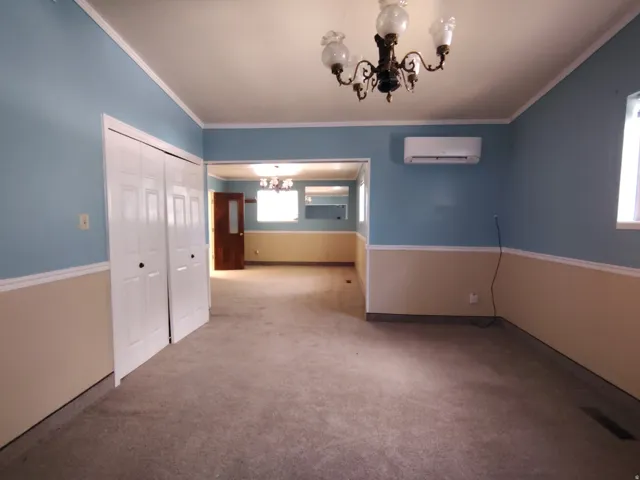 Carpeted interior with two-tone wall paint, crown molding, and a decorative chandelier