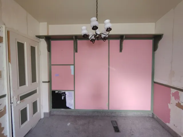 Interior space featuring a paneled wall with a decorative shelf and support brackets, a multi-paneled door, and a ceiling-mounted light fixture