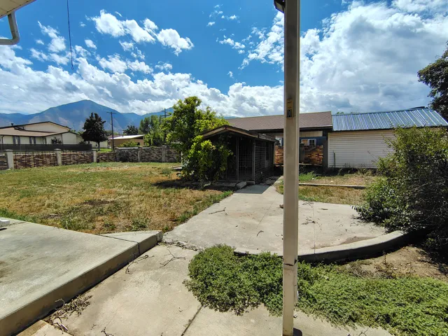 Expansive yard space with concrete patio areas, mature trees, and mountain scenery
