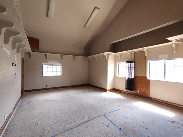 Vaulted ceiling room featuring multiple windows, built-in shelving with decorative corbels, and wood paneling accents
